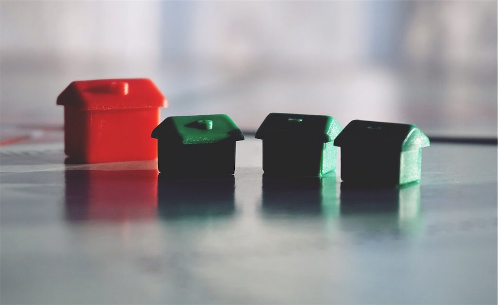 Image of four miniature houses used to illustrate and compare hdb loans and bank loans