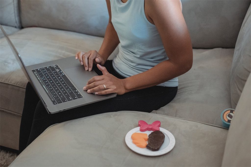 Woman sitting on a couch and searching for a resale flat in Singapore through her laptop