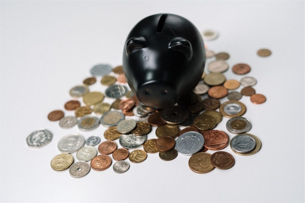 A black piggybank on top of a bunch of coins, signifying an increase in income to boost TDSR