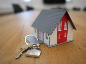 Image of a house key and a miniature house made of cardboard in Singapore, where a home loan is needed to buy a property